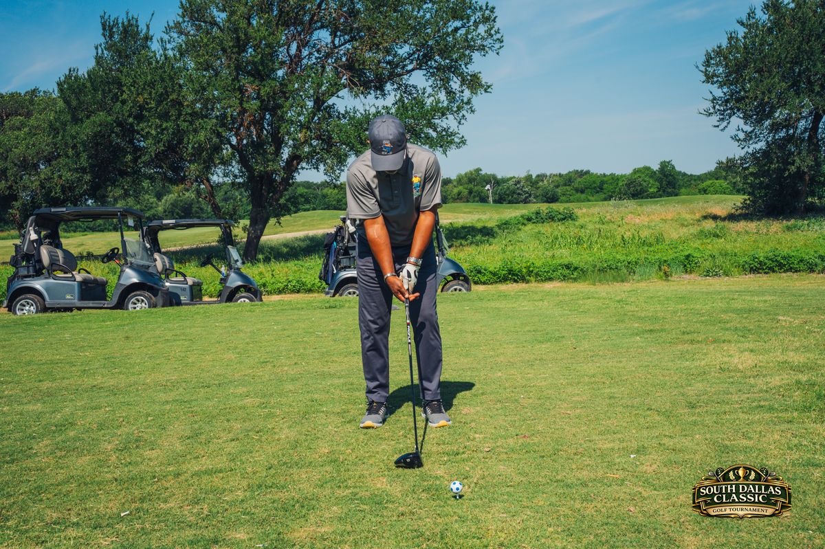 Golfer teeing up with golf carts in background
